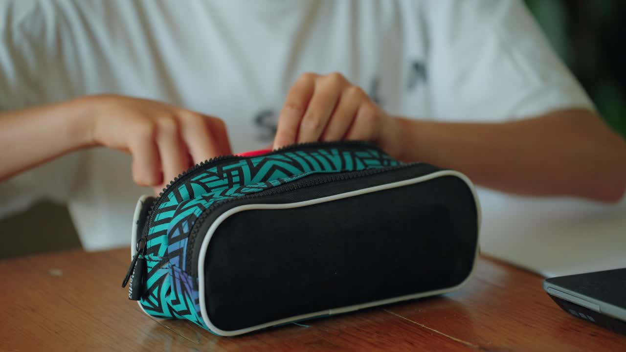 niño de la escuela que busca en su bolsa estacionaria un bolígrafo