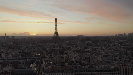 Aerial-footage-of-Eiffel-Tower-protruding-high-above-other-development-in-urban-borough.-Silhouette-against-colourful-sunset-sky.-Paris,-France