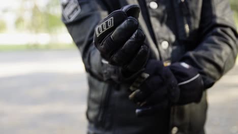 man dressed up in professional motorcycling clothes wearing gloves in forest in slow motion during golden hour