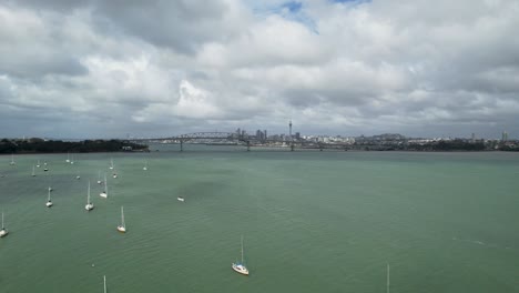 Toma-Aérea-Sobre-El-Puerto-De-Auckland-Con-Yates-Con-Vistas-Al-Puerto-De-Waitemata-Y-Al-Horizonte-Del-Centro-Desde-Una-Plataforma-Rodante-Aérea-A-Través-De-Las-Aguas-Turquesas.