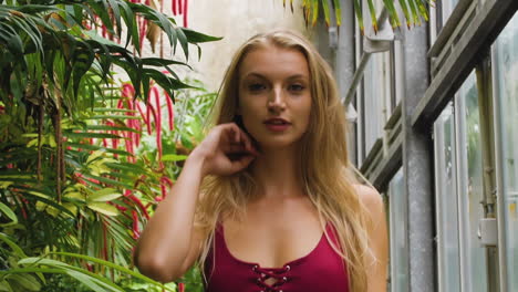 close-up of a caucasian blonde, swimwear model, walking and smiling in a botanic garden