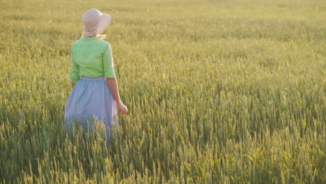 a woman farmer admires the endless field of green wheat organic farming concept 4k video