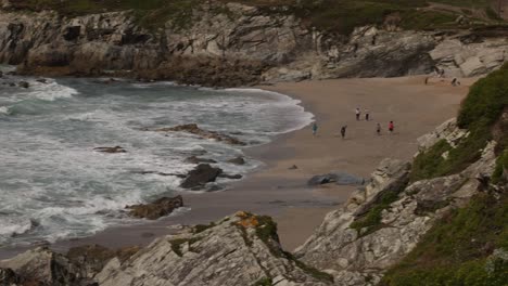 Toma-Panorámica-Lenta-De-Turistas-En-La-Pequeña-Playa-De-Fistral-Disfrutando-De-Las-Vistas.