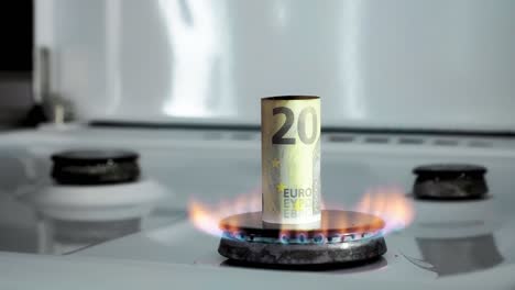 concept of gas crisis. 20 euro bill is burning on a kitchen stove burner. european cash money. high prices of natural resources. fire flame. utility debt. energy war. saving home budget.