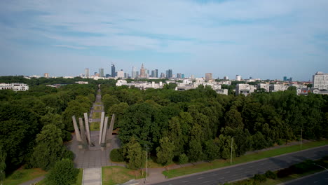 aerial wide shot of forest avenue and skyline of warsaw during sunny day in background, poland - panorama view