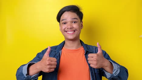 young man in casual style showing thumbs up and dance isolated on yellow background