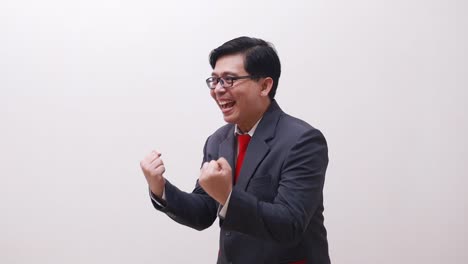 wow excited asian businessman standing while celebrating his success with fist or clenching hands