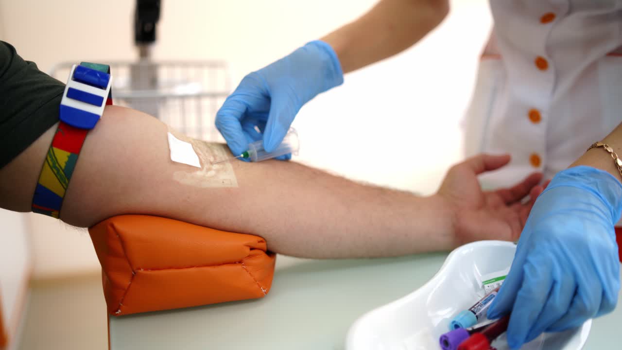 Injection during the blood collection. Nurse taking blood sample from patient at the doctors office