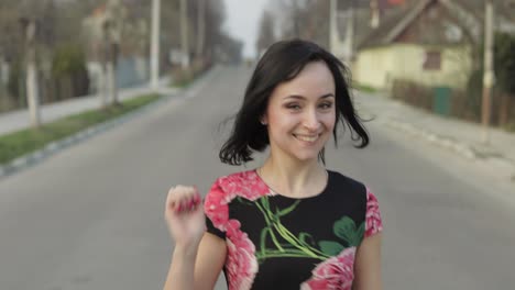joven atractiva en un vestido con flores moviéndose hacia la cámara y sonriendo