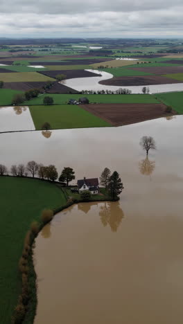 aerial view of a house and farmland submerged by extensive flooding
