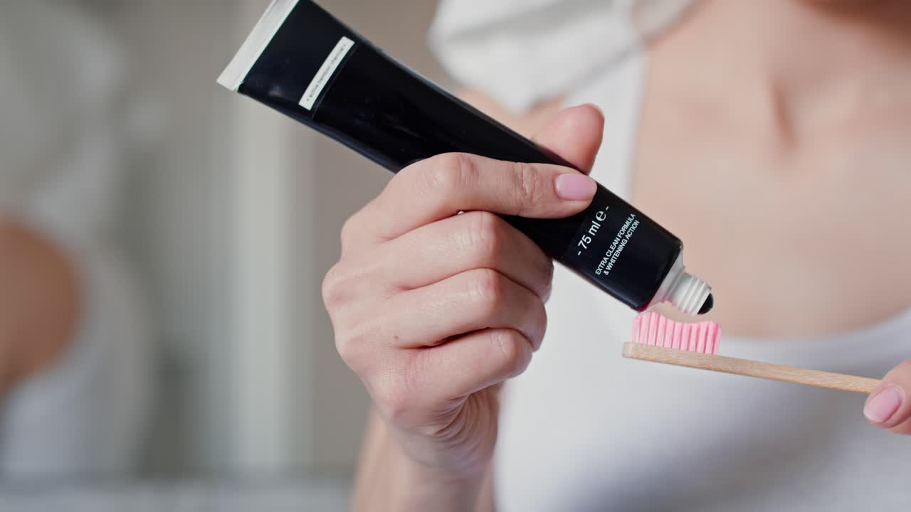 detalle de una mano irreconocible aplicando pasta de dientes en el cepillo de dientes.