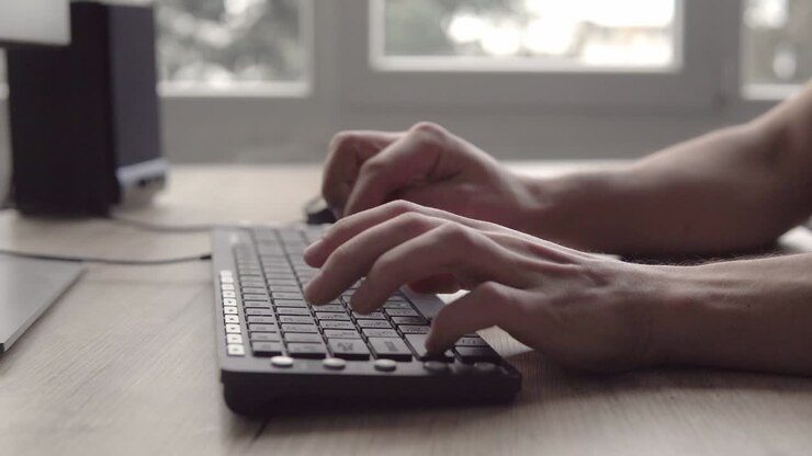 Tippen auf einer Tastatur. Mann tippt auf Computertastatur. Männerhand benutzt Computertastatur und Maus zum Tippen. Freiberuflicher Fotograf arbeitet am Computer.