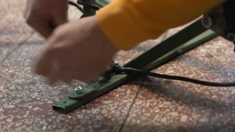 close-up of hands connecting black electrical cables near a bicycle wheel for repair work