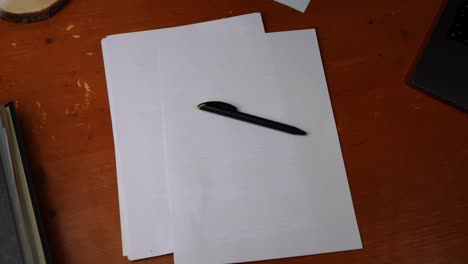 black-pen-is-put-on-a-table-with-white-paper-and-taken-away