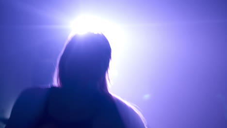 Silhouette of a Woman Dancing Under Bright Lights