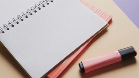 close up of open notebook with school stationery on beige and blue background, in slow motion