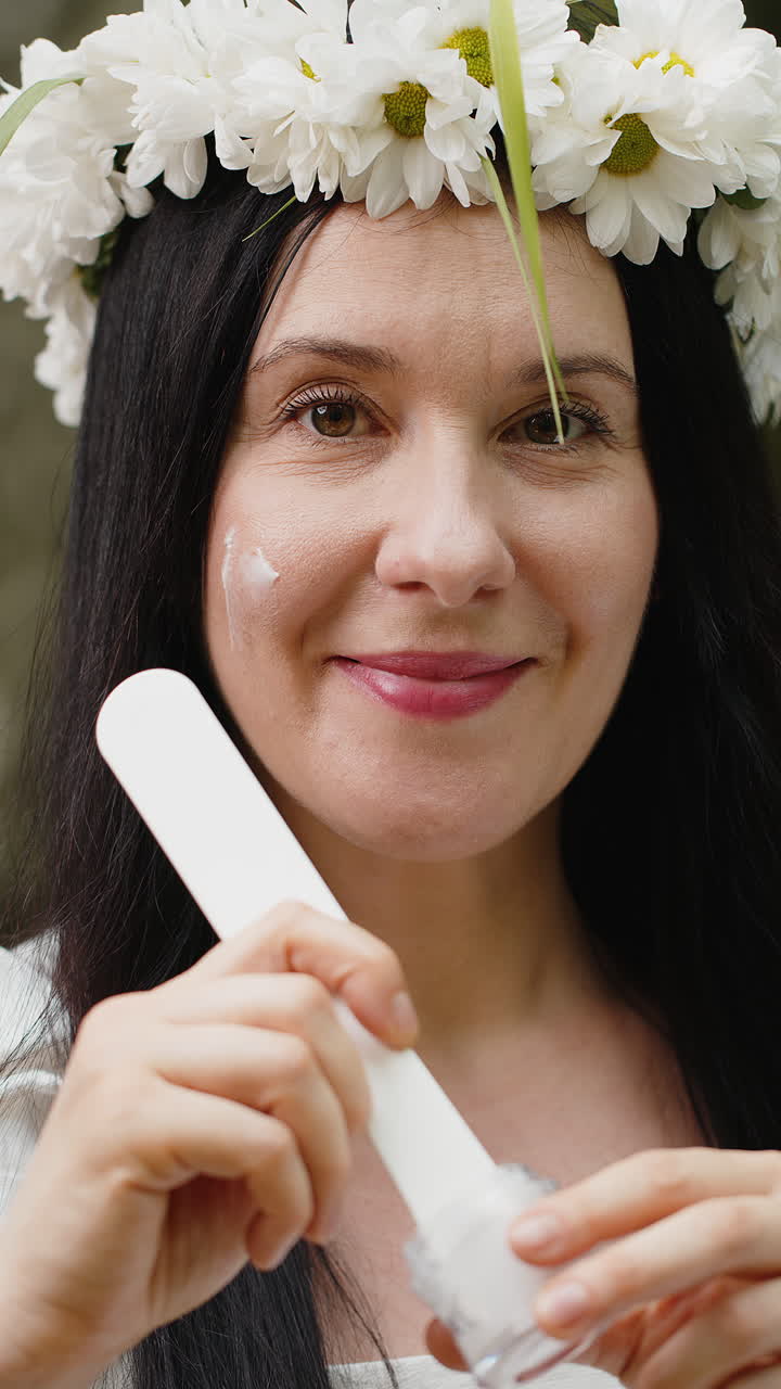 feliz 40 años de edad madura mujer de mediana edad aplicando la piel facial crema hidratante tratamiento de belleza