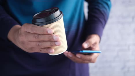 person holding coffee and using phone