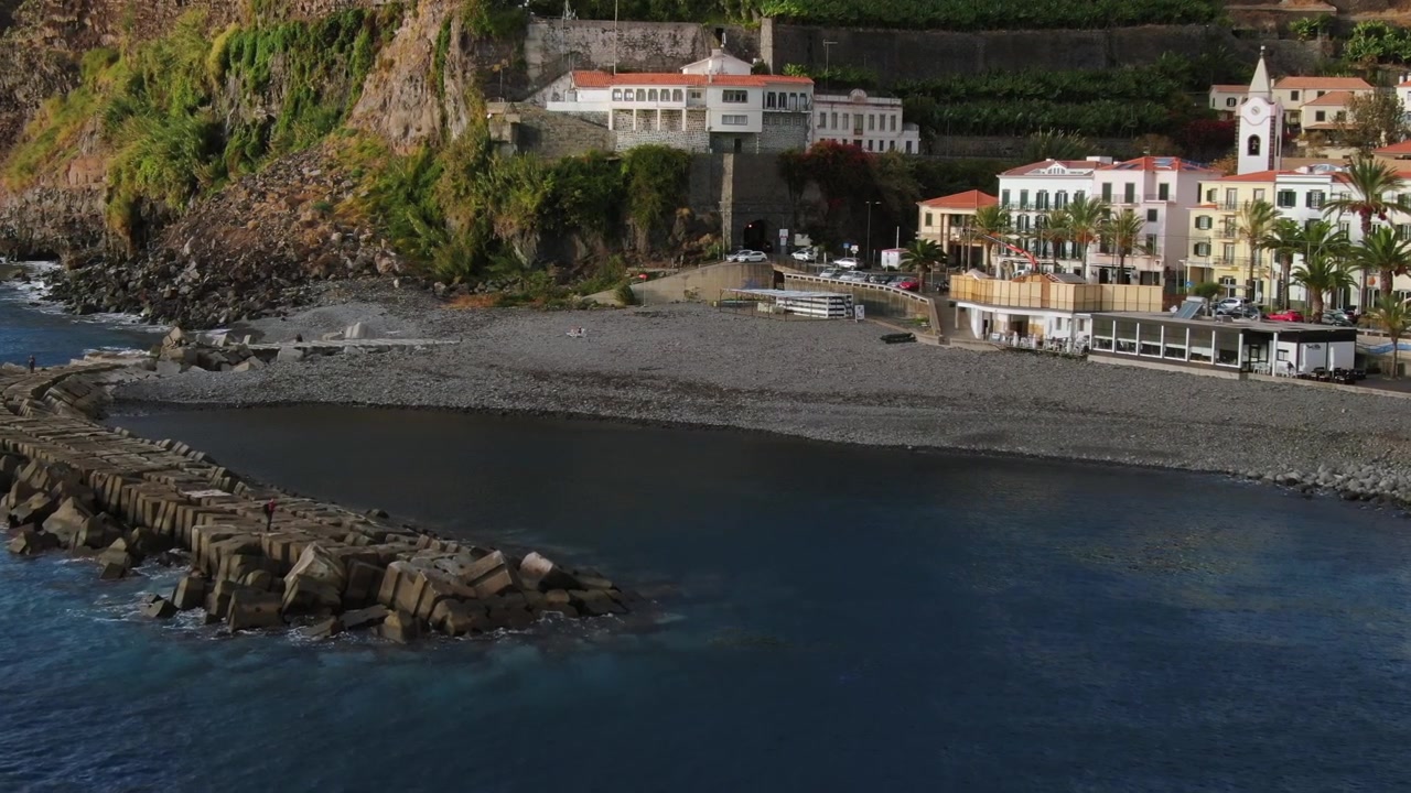 Suggestivo villaggio costiero di Ponta do Sol a Madeira, Portogallo, con il suo storico molo, la spiaggia di ciottoli e i suggestivi edifici costieri.