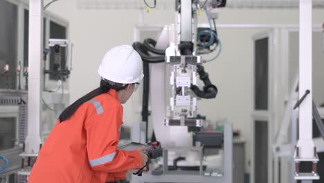 the professional officer check the robot moving  on the jig base on manufacturing factory. repairing robotic arm in research lab, wearing protective eye wear, using computer check the loop of program.