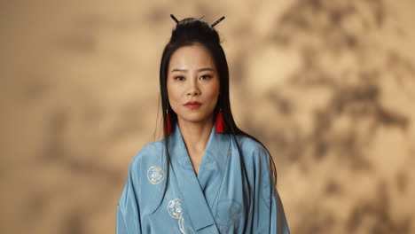 young asian woman in blue kimono looking to camera with serious expression