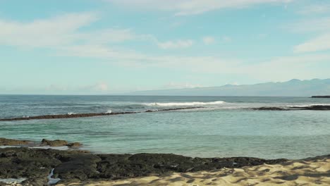 large tide pool with waves splashing over the lava rock reef