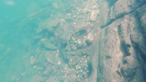 pov dive to bottom of cliff under blue lake, swim back up in sun rays underwater