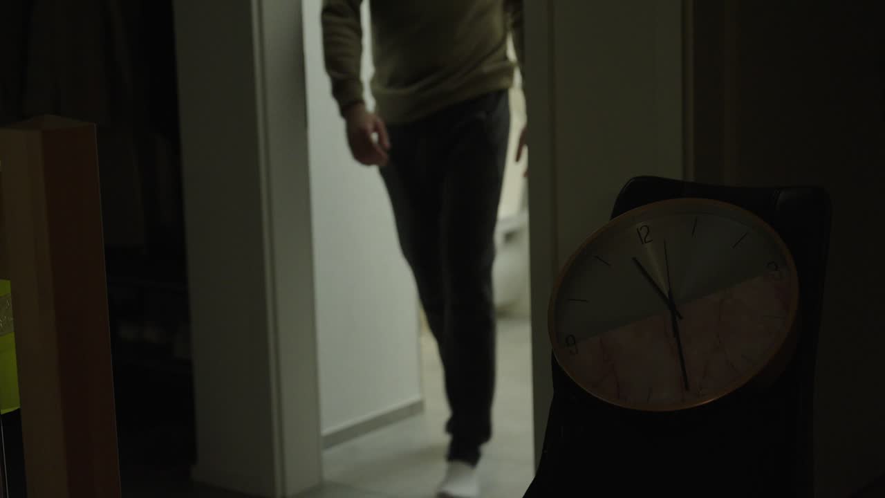 Scena notturna sfocata con effetto bokeh, che mostra una lavastoviglie in funzione rumorosamente mentre un vicino è disturbato dal rumore. Concetto di disturbo notturno, rumore casalingo, vita in appartamento e interruzione del sonno.