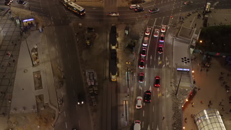 Descending-and-tilt-up-footage-of-vehicles-driving-through-road-intersection-in-evening-rush-hour.-Warsaw,-Poland