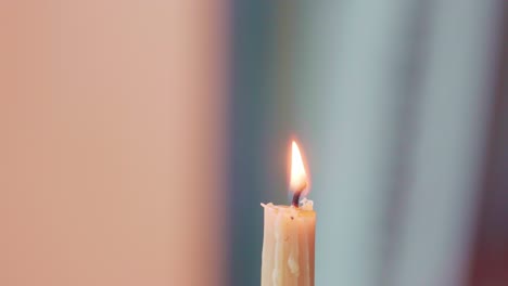 closeup on artist's hand holding a wax stylus in a candle flame