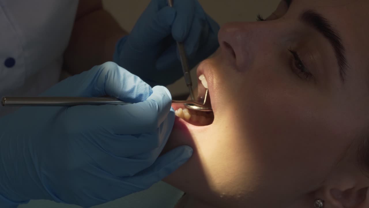 Dentist's hand examining teeth with special dentist instruments in the special light