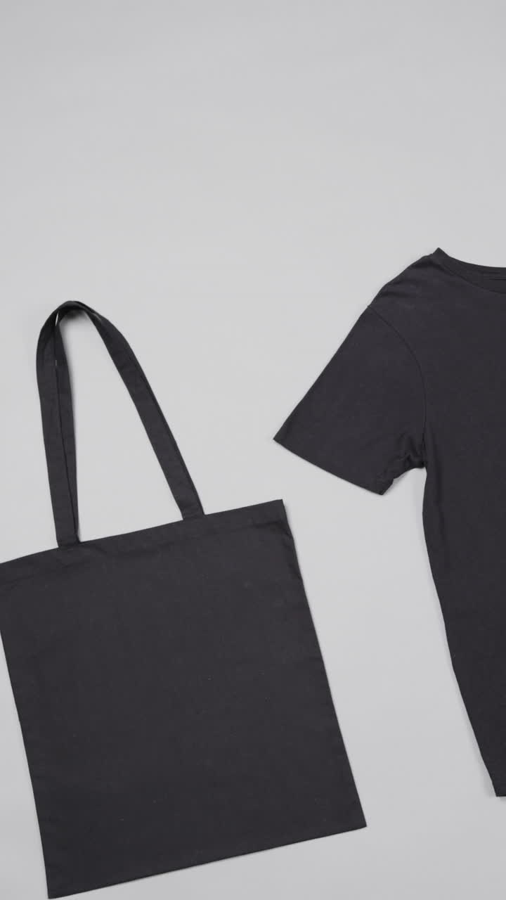 Vertical video of black canvas bag and t shirt with copy space on white background