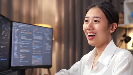 close up of asian woman programmer smiling to camera while creating software engineer developing app, program, video game on desktop computer at home. terminal with coding language