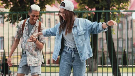 full length view of a teenage girl riding a skateboard while her african american boyfriend helping her maintain balance in the street