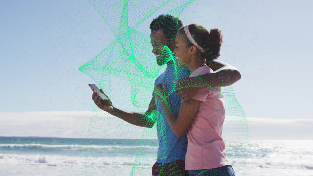 Couple hugging on sandy beach, sharing smartphone in tech mapping session, using green mesh overlay