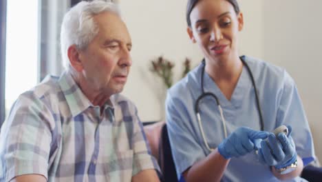 video de una feliz médica biracial chequeando el nivel de glucosa a un anciano caucásico