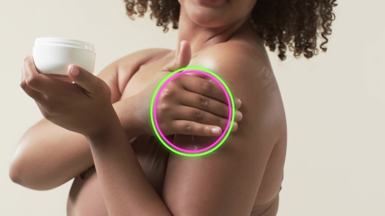 Woman scooping cream from jar, smoothing shoulder while rings pulsing over area for skincare