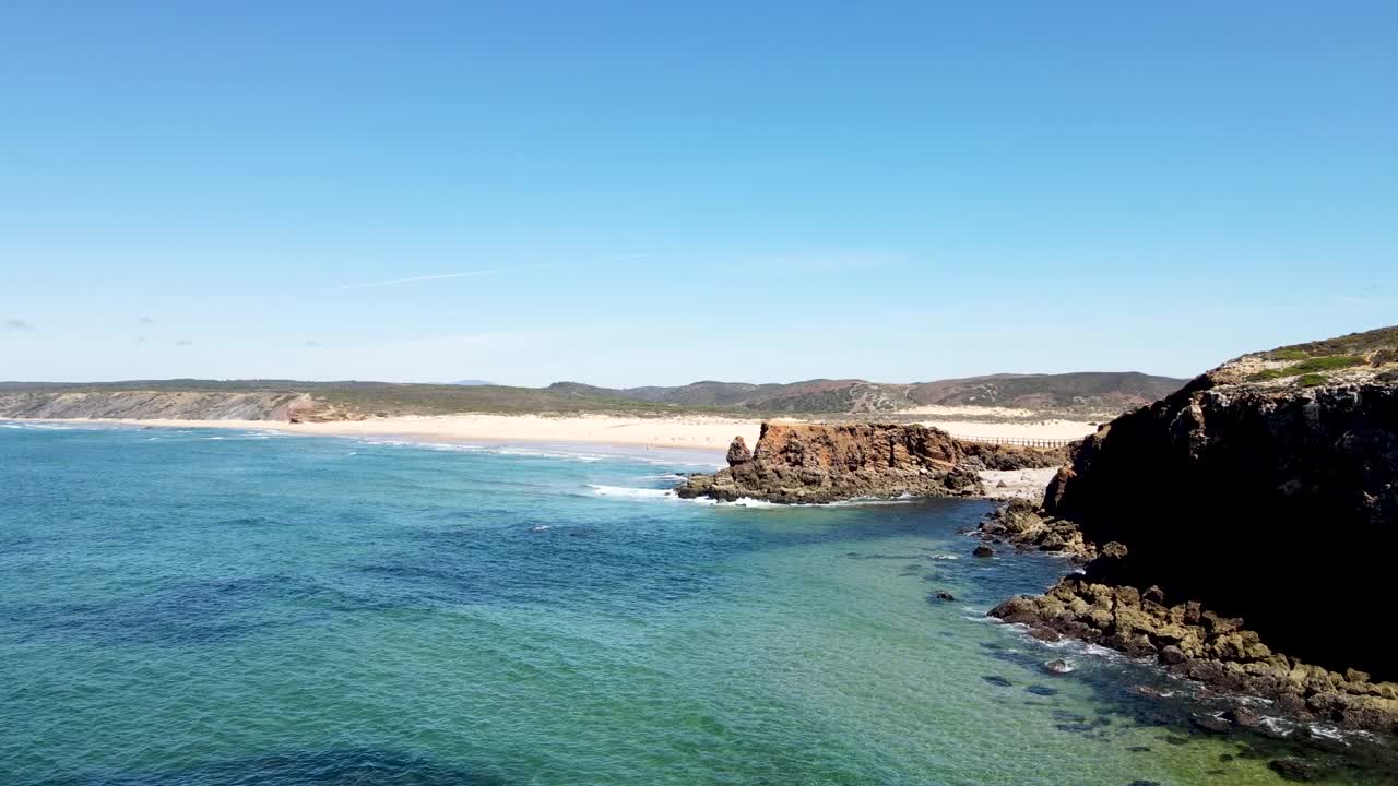 volar lentamente sobre los acantilados y el agua con la playa en el fondo en portugal