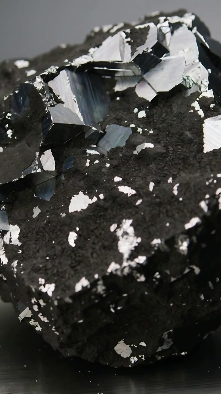 Vertical video: Zooming camera showing mineral rock on studio base, revealing silver crystal faces