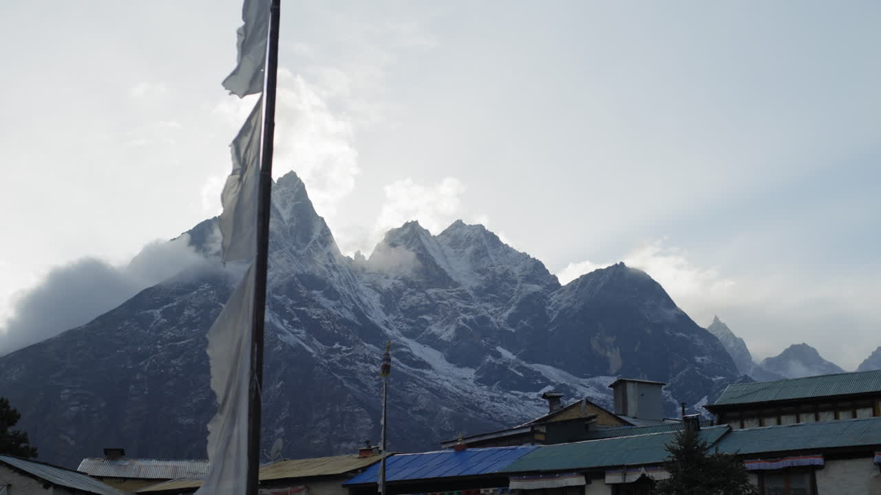 tiro de deslizamiento de himalaya con bandera de oración soplando en el viento desde el pueblo