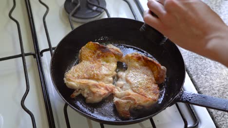 adding salt and pepper to white meat simmering in a pan of oil