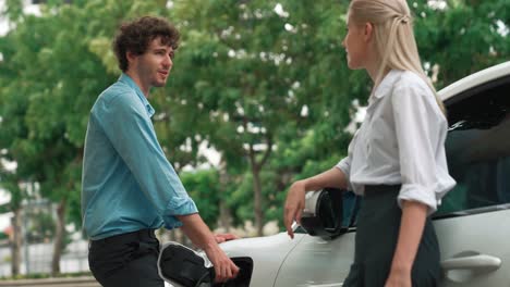 Progressive-businessman-and-businesswoman-use-charging-station-for-EV-car.