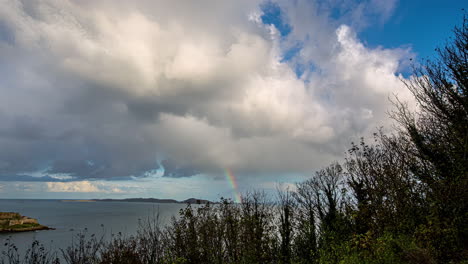 time lapse of rainbow appearing in the clouds over the sea