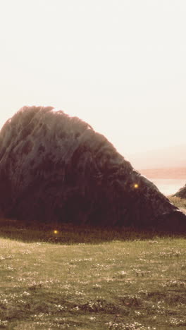 mysterious dark rock in a field at sunset