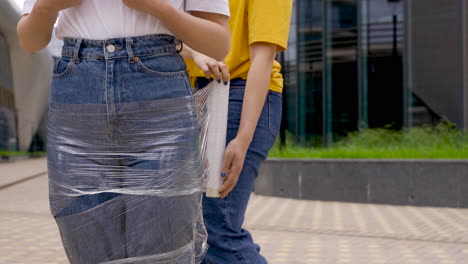 woman wrapping an girl with plastic film