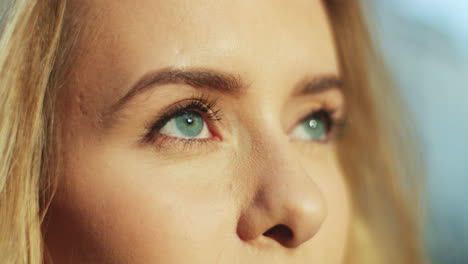 Close-up-view-of-charming-young-blonde-woman-with-blue-eyes-looking-up-with-dreaming-face