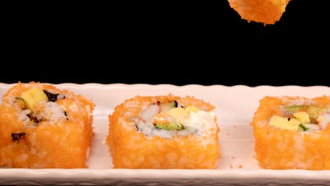 chopsticks pick up a california roll sushi piece from a neatly arranged row on a white plate, set against a black background with bright, even lighting