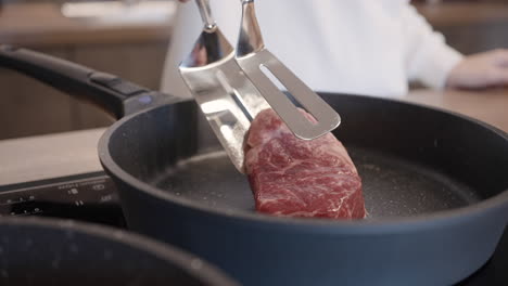 woman cooking steak in a pan