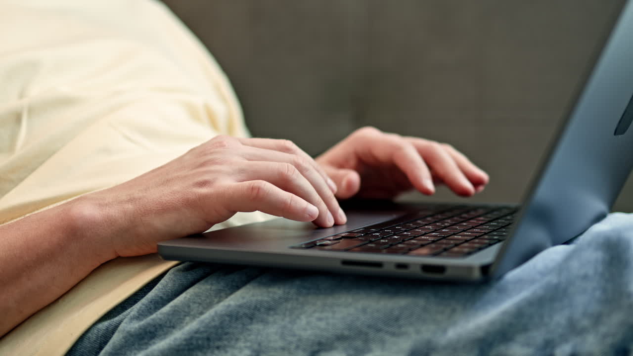 Person typing on laptop while resting in relaxed position at home in the afternoon
