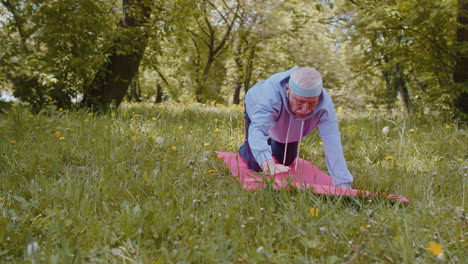 Happy-senior-grandfather-man-exercising,-making-yoga-exercise,-practicing-sports-training-at-park